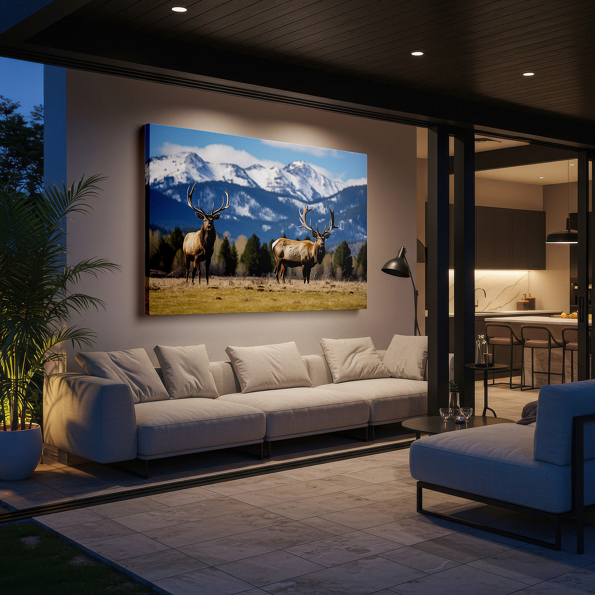 Displayed above a contemporary leather sofa in warm light — majestic elk in expansive grassy field with snow-capped mountains panoramic large wall art, canvas wall decor for office and bedroom